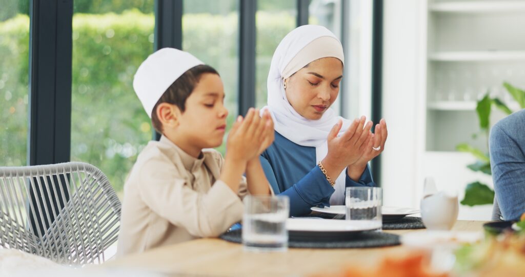 Woman and boy praying at dining table