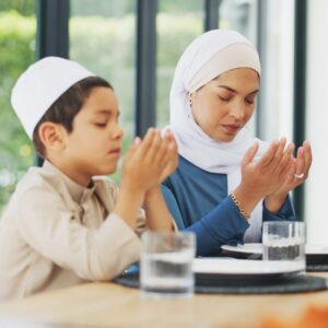 Woman and boy praying at dining table